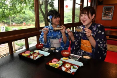 アユの塩焼きを頬張る女性の画像 アユの塩焼きを頬張る女性の画像