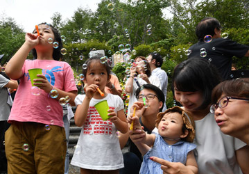 御巣鷹の尾根の昇魂之碑の前でシャボン玉を飛ばす子どもたちの写真 御巣鷹の尾根の昇魂之碑の前でシャボン玉を飛ばす子どもたちの写真