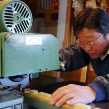 最新の機械を使って組子細工の材料を裁断する高田さん