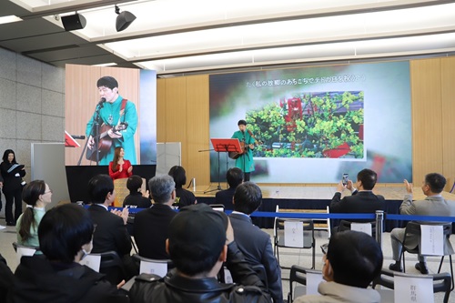 写真：弾き語りで歌う山本知事