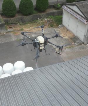 ドローンが牛舎の屋根に石灰を撒いている画像です。